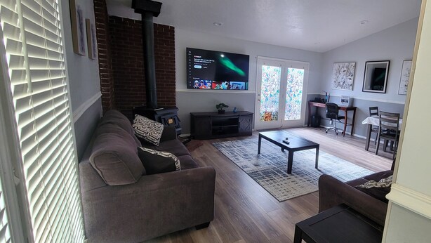 A living room with a sofa, coffee table, and TV. There is a fireplace, a desk, and a chair. -  Entire Townhouse 1 Car Garage +Jacuzzi (West Wendover)
