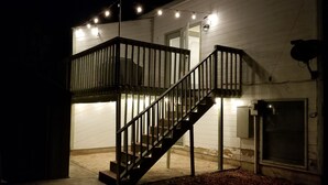 A two-story building with a wooden exterior, a metal staircase, and string lights. -  Entire Townhouse 1 Car Garage +Jacuzzi (West Wendover)