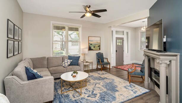 A living room with a sofa, coffee table, and chairs, a fireplace, and a ceiling fan. - SPACIOUS home with 5 bedrooms, 4 bathrooms (Cincinnati)