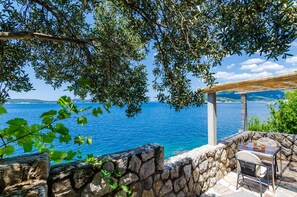 A stone wall with a table and chairs overlooking a body of water.