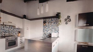 A modern kitchen with a central island, stainless steel appliances, and a tiled backsplash.