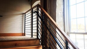Una escalera de madera con barandales de metal negro que da a una plataforma.