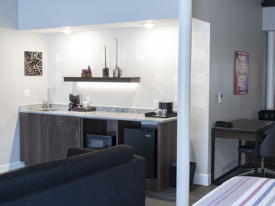 Une chambre d’hôtel compacte comprenant un coin cuisine, un canapé, un petit bureau et un lit.