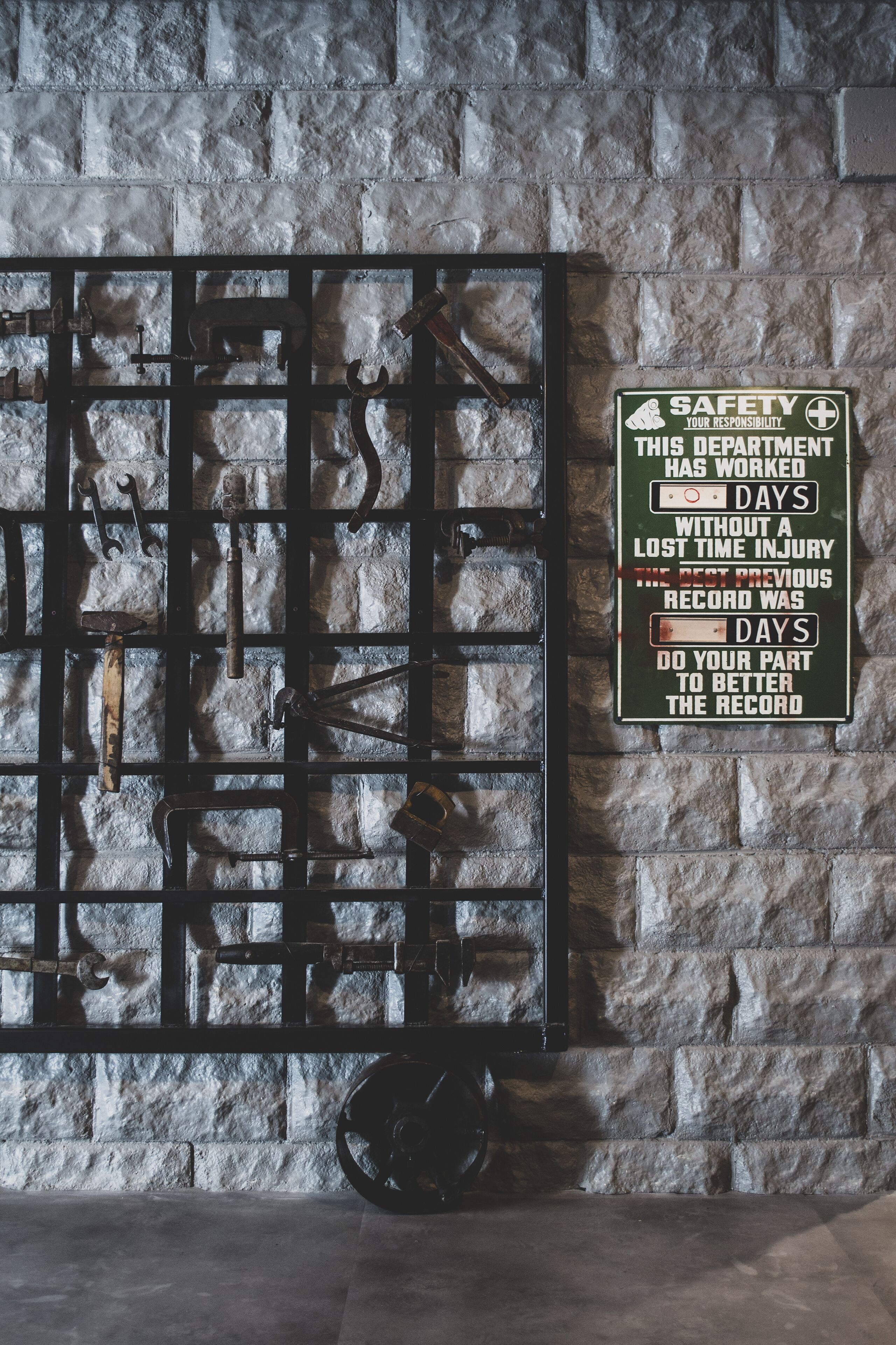 A wall with a metal rack holding tools and a safety sign.