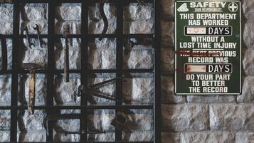 A wall with a metal rack holding tools and a safety sign.