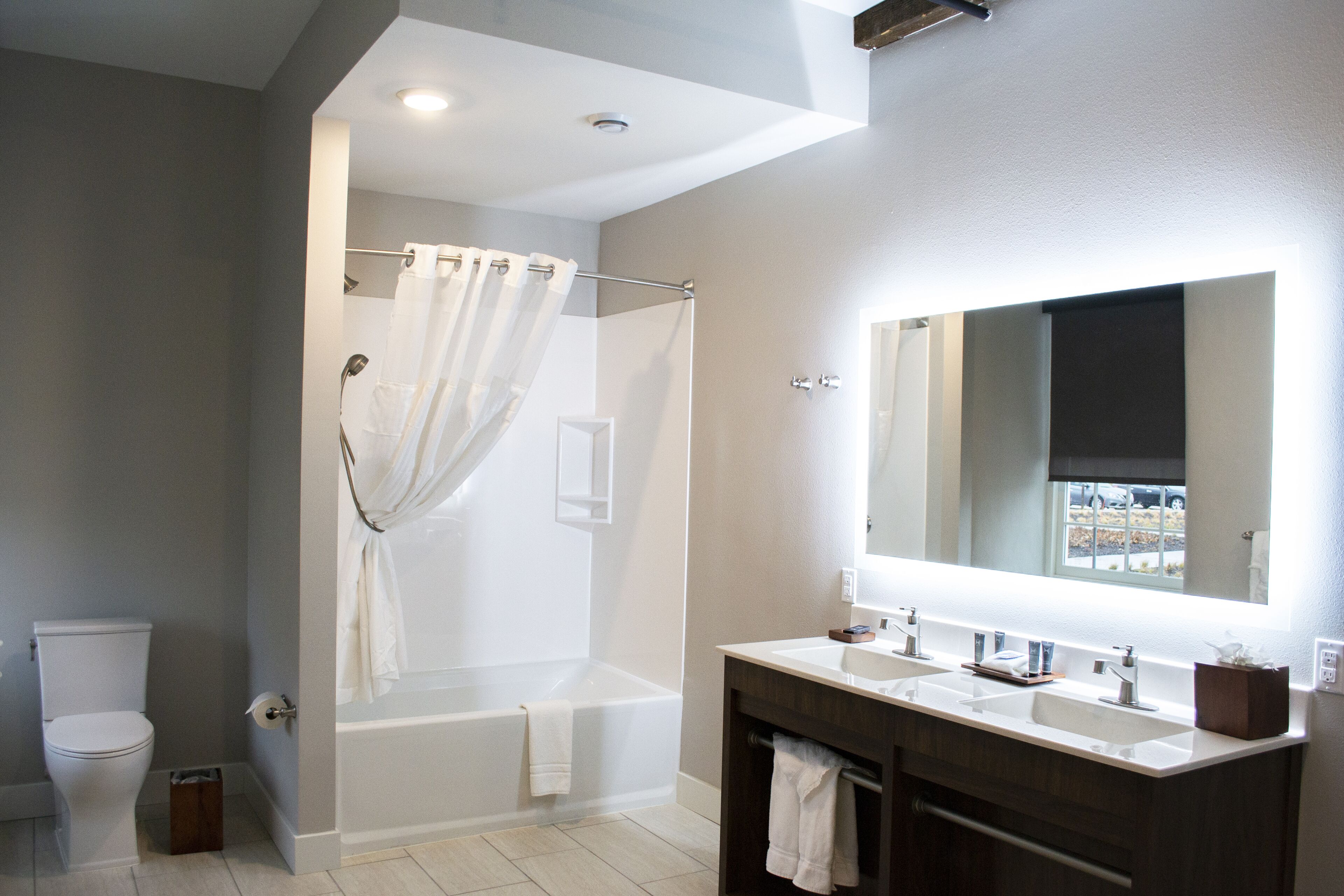 A modern bathroom with a bathtub, a large mirror, and a vanity with a sink.