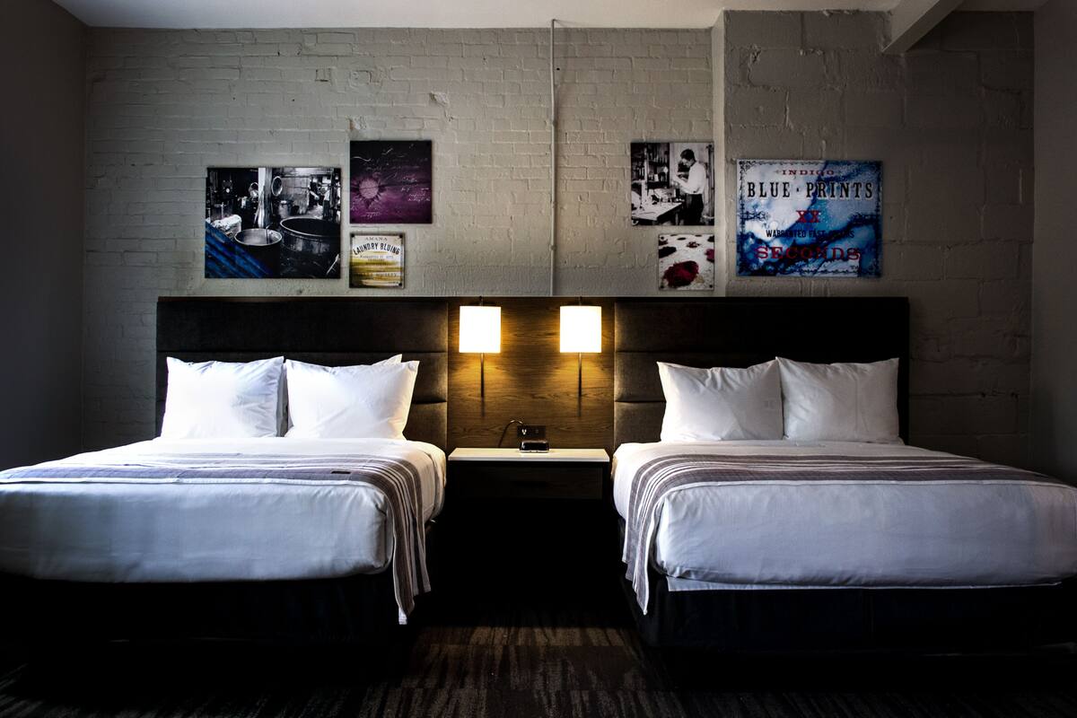 Une chambre d’hôtel avec deux lits, un mur en briques et trois affiches accrochées au mur.