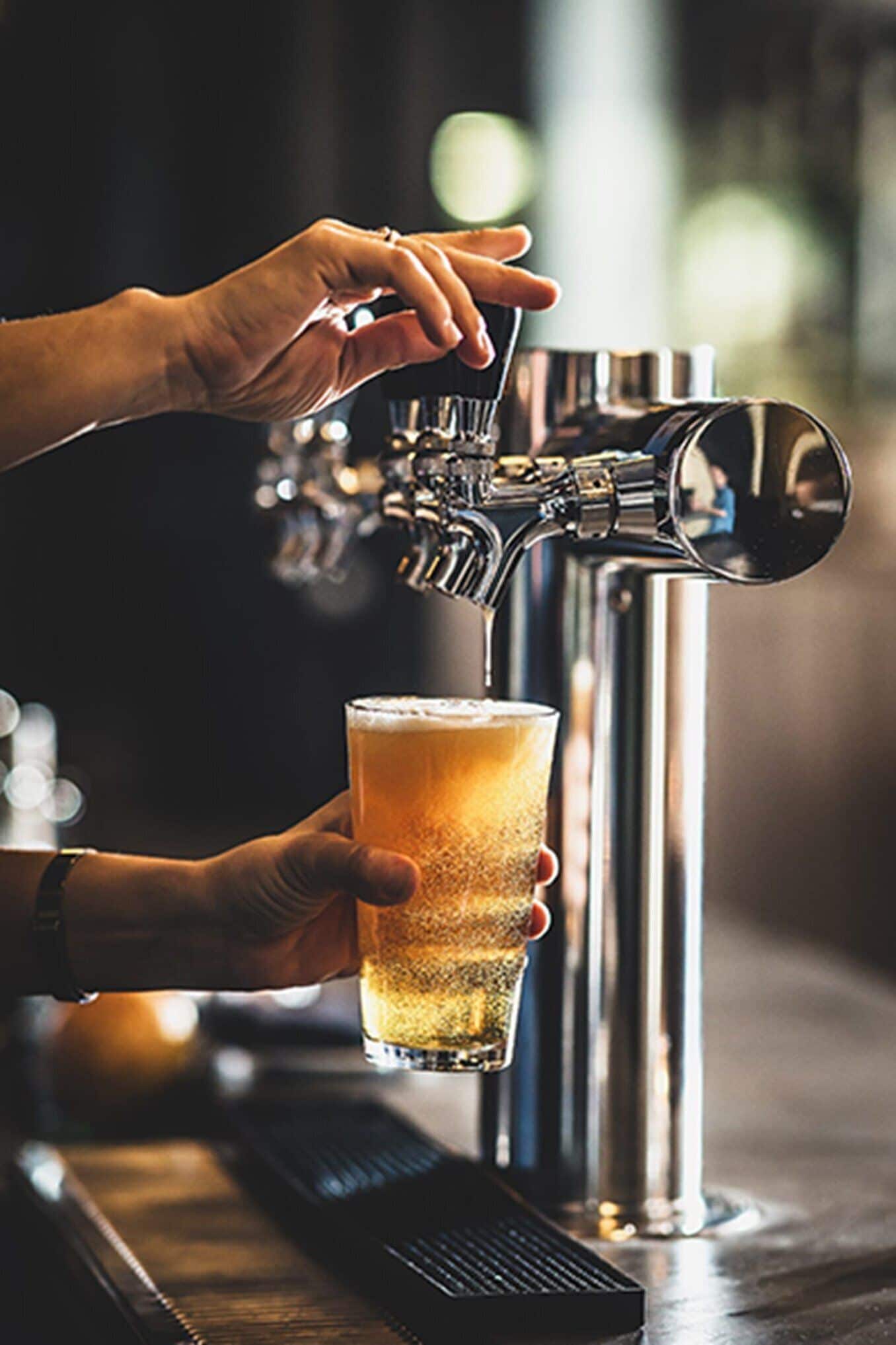 Una mano sosteniendo una cerveza en un grifo.