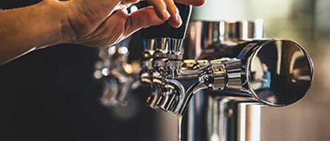 Una mano sosteniendo una cerveza en un grifo.