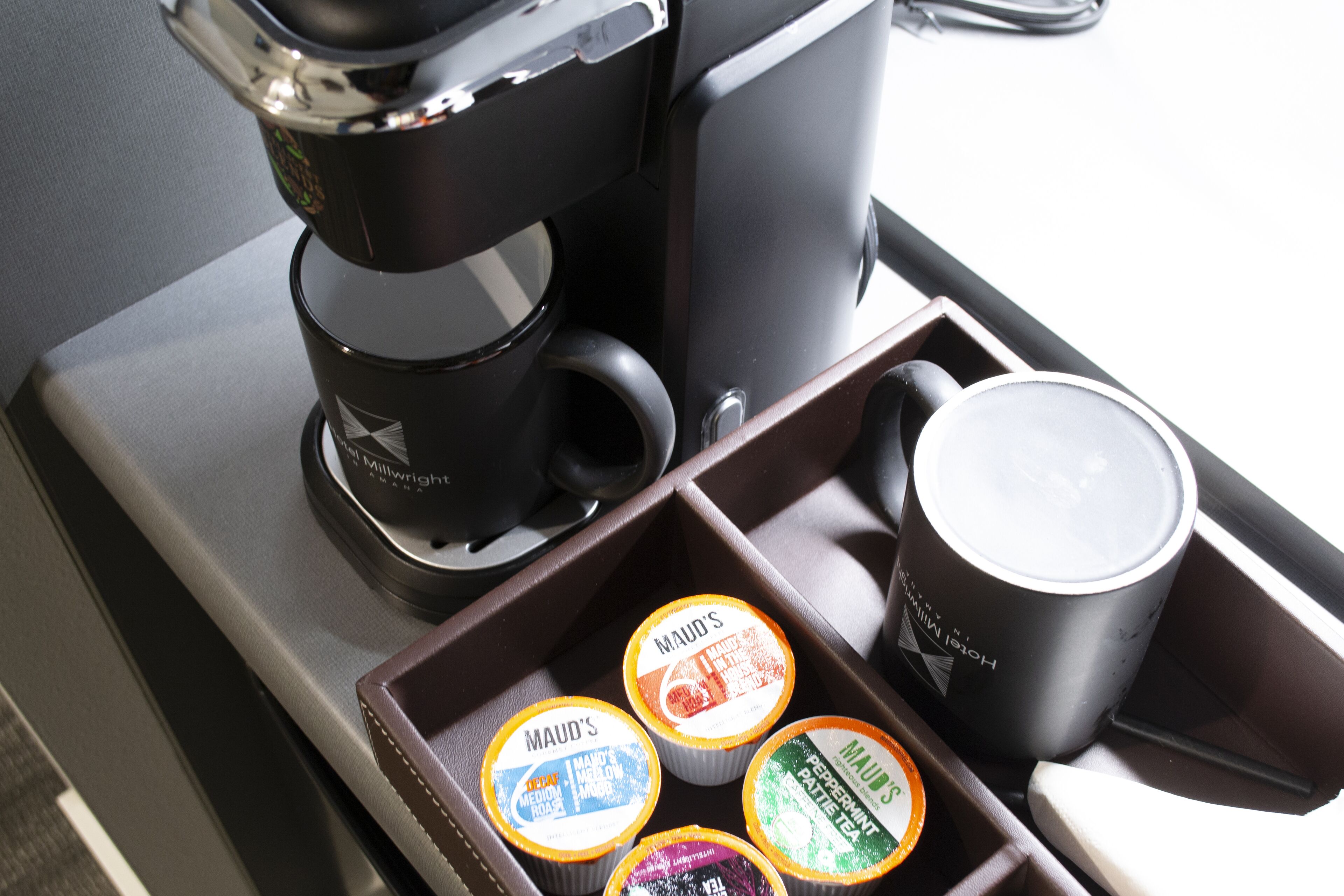 A coffee maker and a tray with four Mauds ice cream containers.