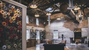 Un loft espacioso con paredes de ladrillo visto, una gran pared llena de objetos circulares e iluminación de estilo industrial.