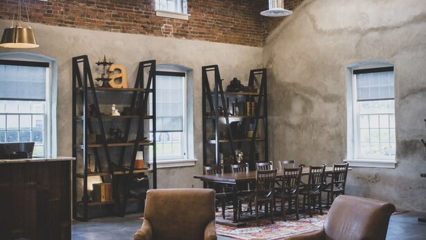 Un loft espacioso con paredes de ladrillo visto, ventanas grandes e iluminación de estilo industrial.