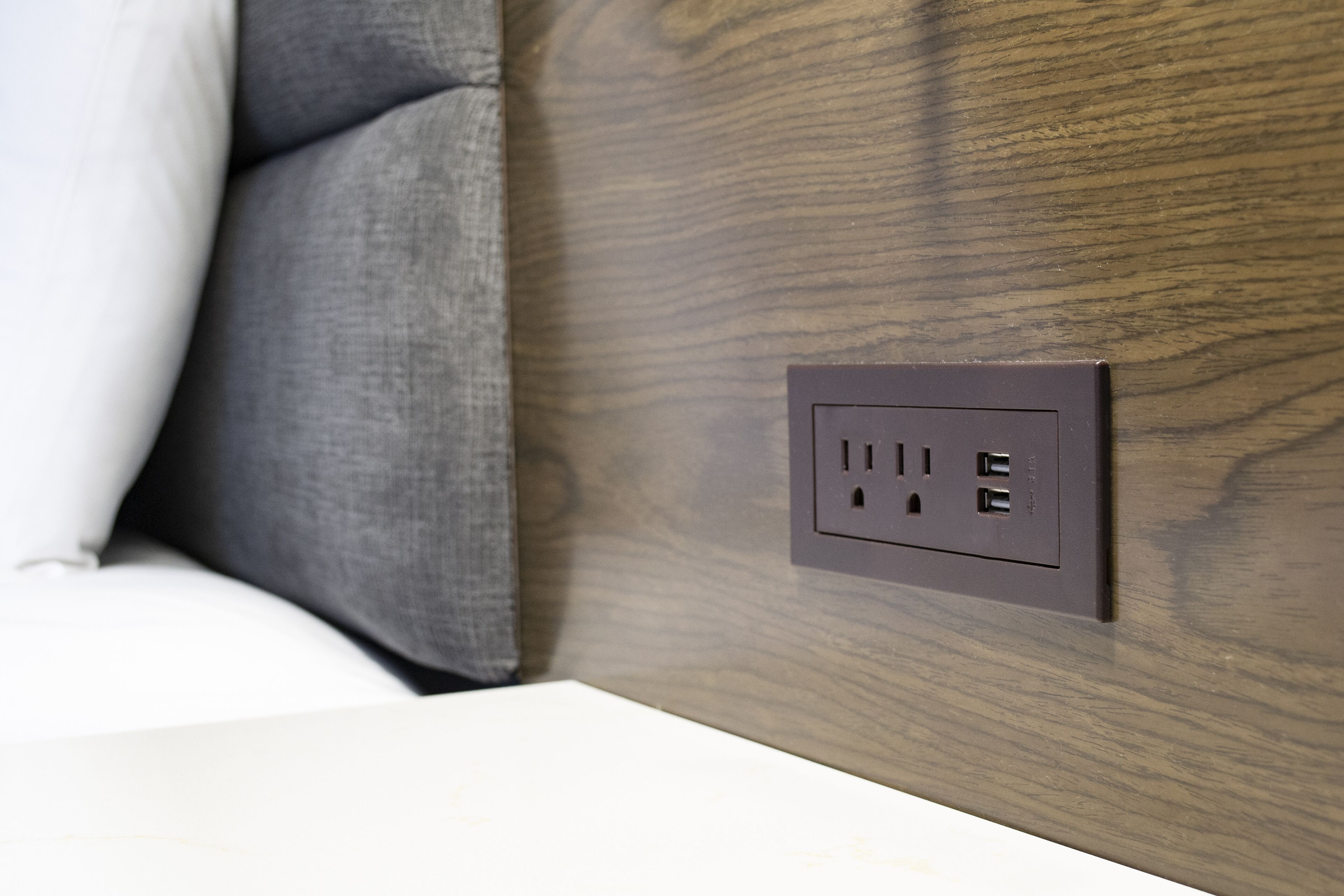 A wall socket with a wooden panel background.