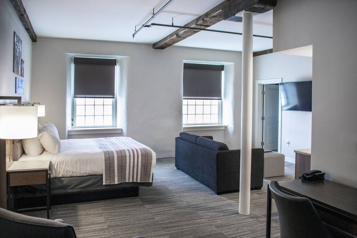 Une chambre d’hôtel moderne équipée d’un lit, d’un canapé, d’un bureau et d’une télévision.