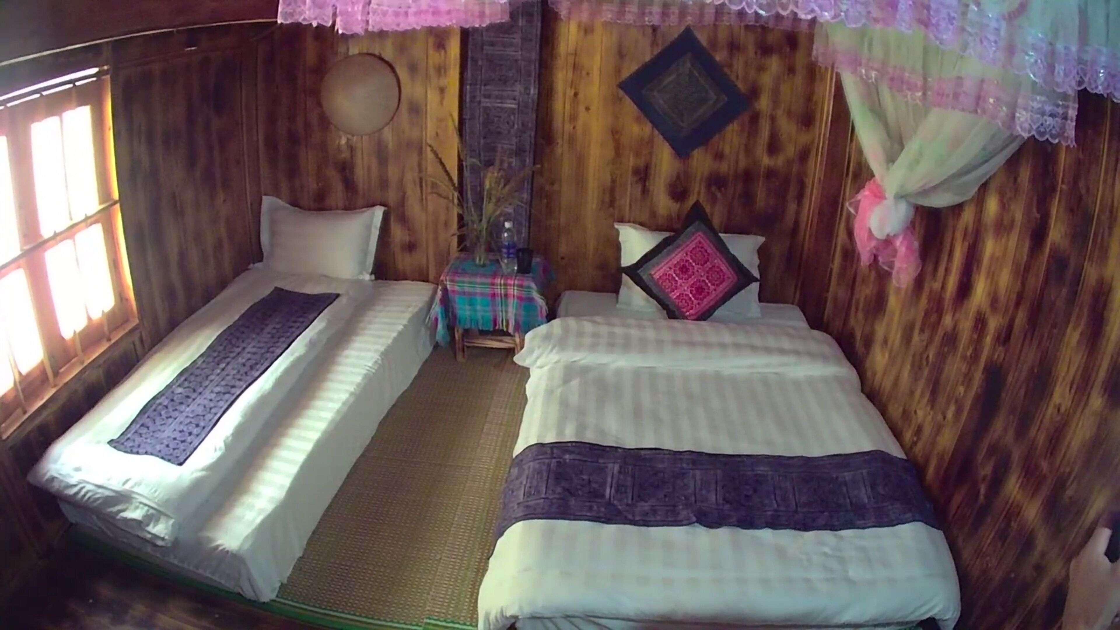 Een kamer met twee bedden, een tafeltje en een decoratief wandobject.