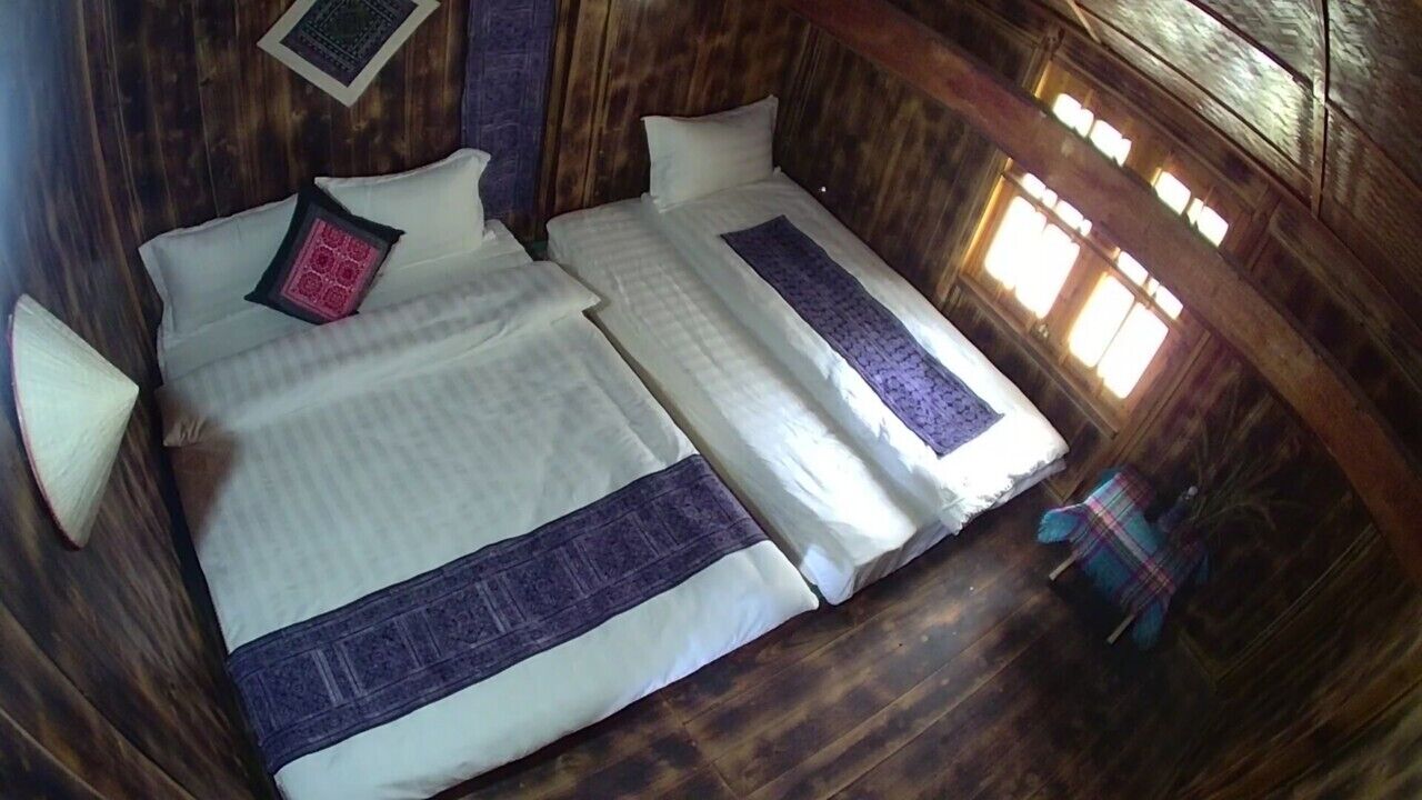 Une chambre avec deux lits, des murs en bois et une fenêtre.