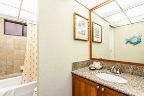 A bathroom with a bathtub, a sink, and a mirror. - Aston Ka'anapali Shores 325 | Lush Garden Views – Pool, Hot Tub & Spa (Lahaina)