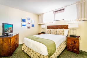 A hotel room with a bed, a television, a nightstand, and a window with curtains. - Aston Ka'anapali Shores 325 | Lush Garden Views – Pool, Hot Tub & Spa (Lahaina)