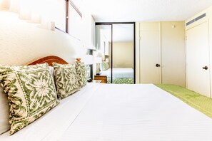 Habitación de hotel con una cama grande, una mesita de noche, un espejo y una puerta corrediza a un balcón.