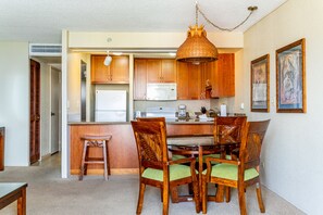 Cozinha compacta com armários de madeira, micro-ondas e área de refeições com mesa e cadeiras.