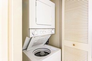 A front-loading washer and dryer unit in a laundry room with a door to the right.