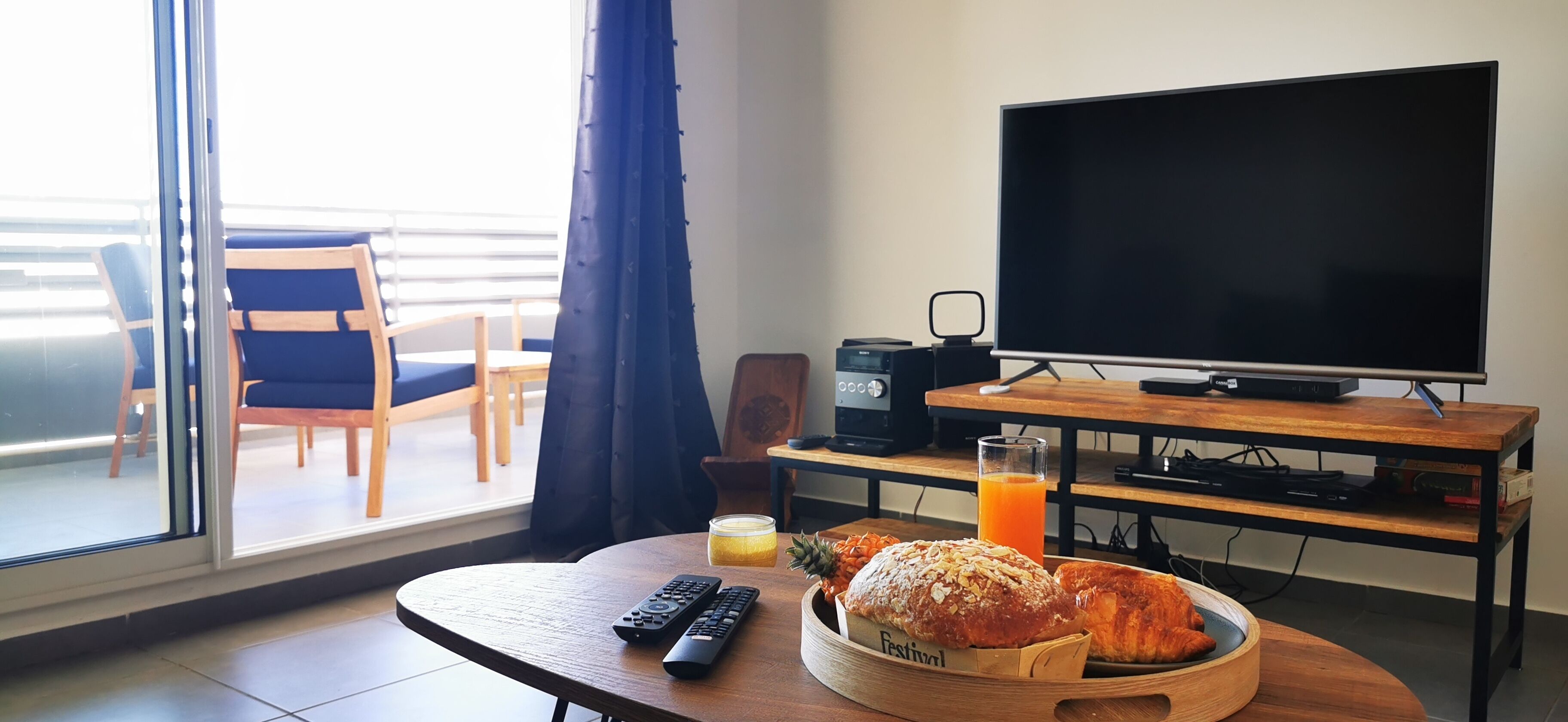 Et hotelværelse med fjernsyn, et træbord med morgenmad, et TV-bord og udsigt til den udendørs balkon.