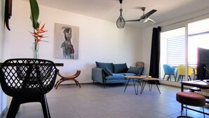 Un salon moderne comprenant un canapé, une table basse et un coin repas avec des chaises.