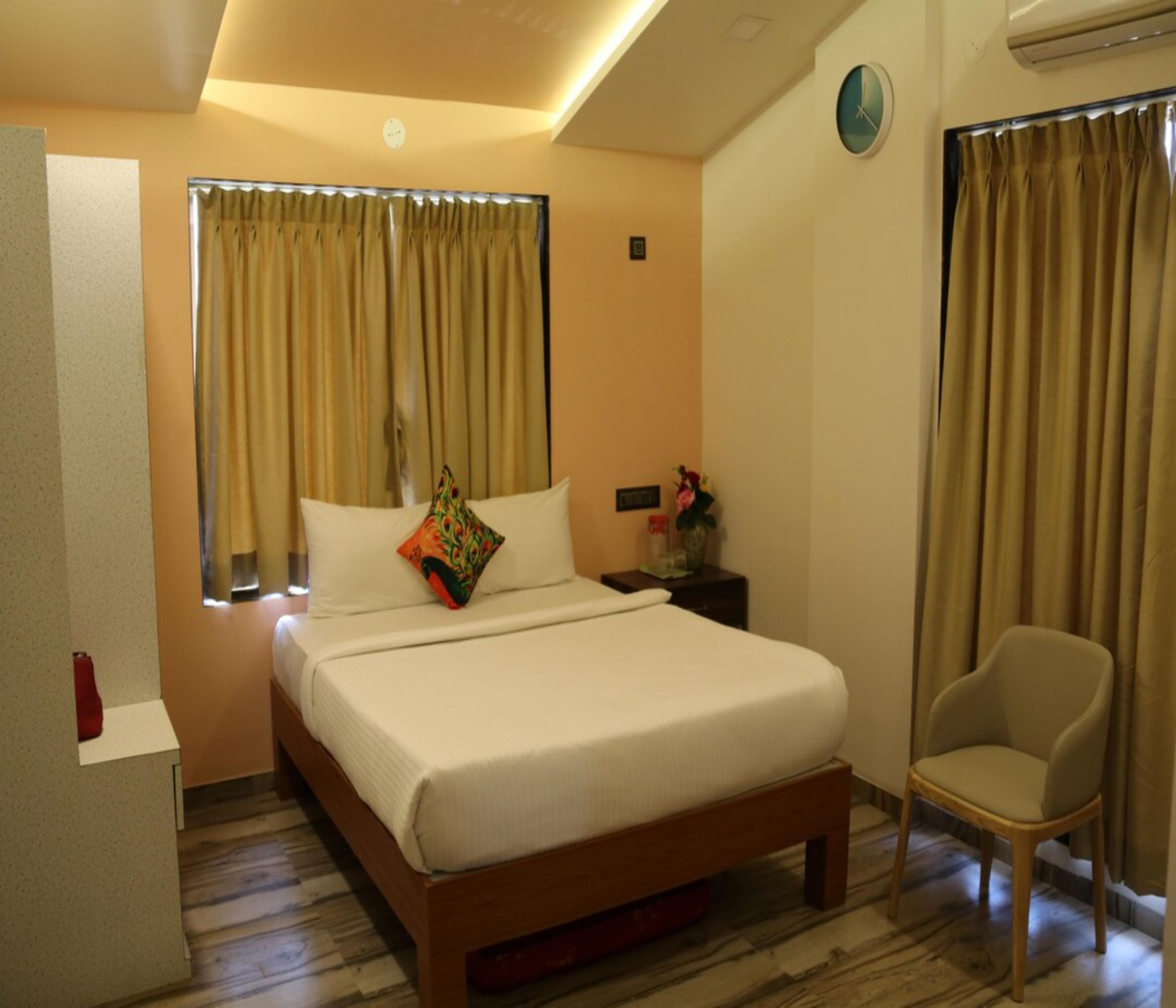 A hotel room with a bed, a chair, a nightstand, and curtains.