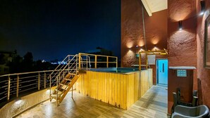 A wooden deck with a pool, a staircase, and a door leading to an elevator.