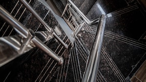 A spiral staircase with metal railings and a dark, polished floor.