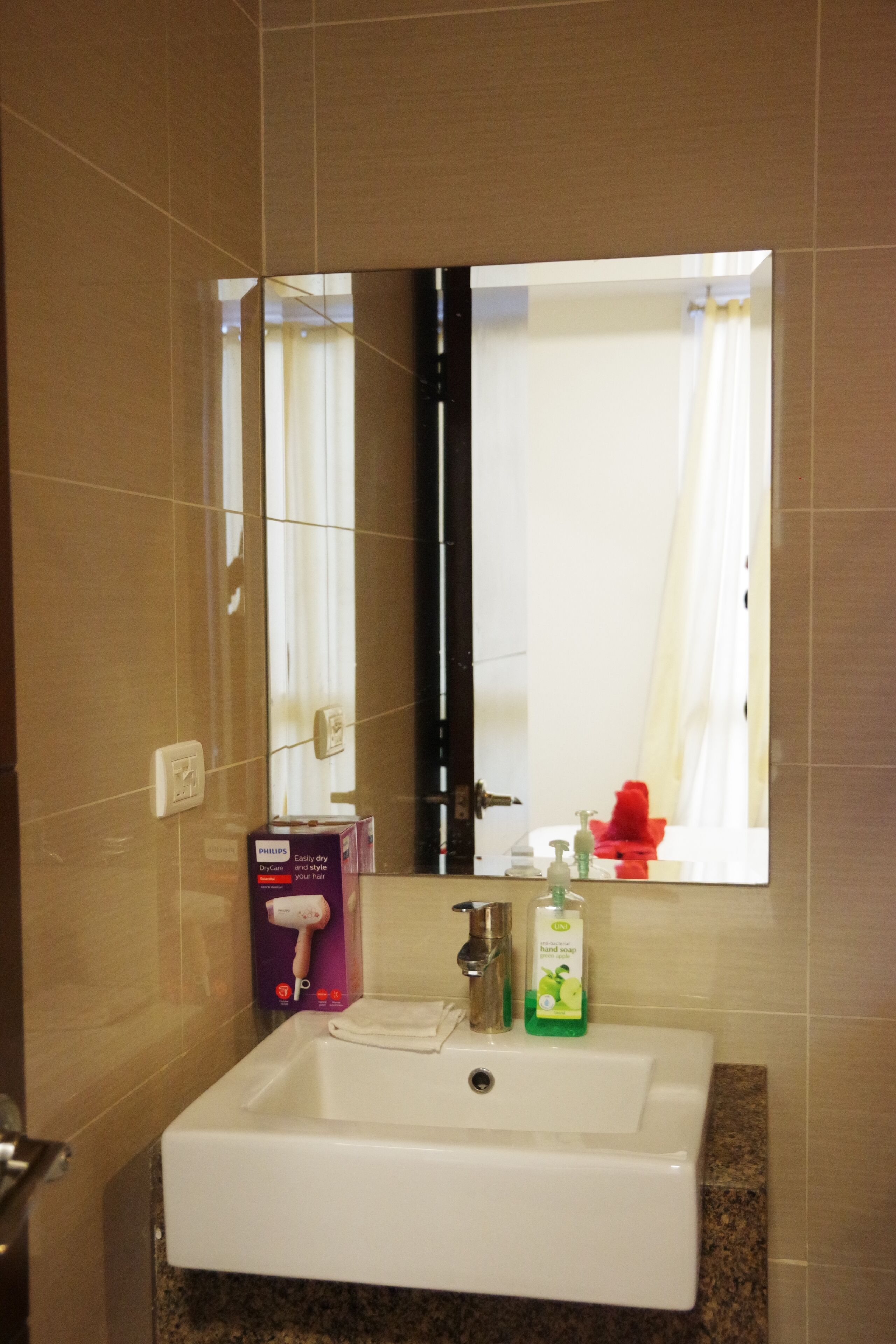 A bathroom with a white sink, a mirror, and a hand soap dispenser.