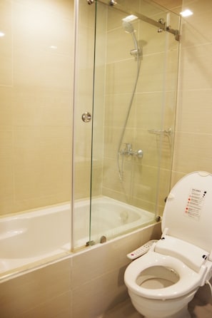 A bathroom with a glass-enclosed shower, a bathtub, and a toilet with a control panel.