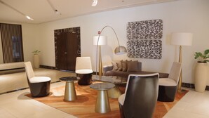 Una sala de estar moderna con un sofá, sillas, una mesa de centro y una lámpara de pie.