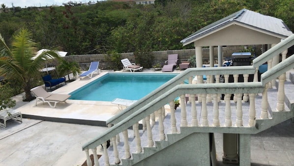Relax by the pool surrounded by a scenic view and outdoor dining area.