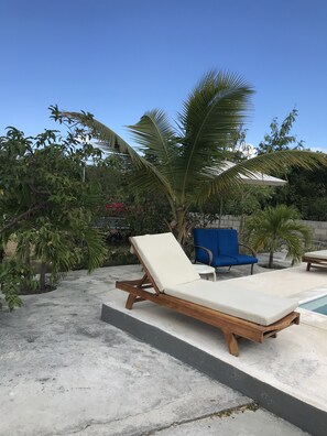 A poolside area with lounge chairs, a small pool, and tropical plants. - Comfy Apartment 15E in quiet Sagusta Gardens PLS with pool view (Providenciales)