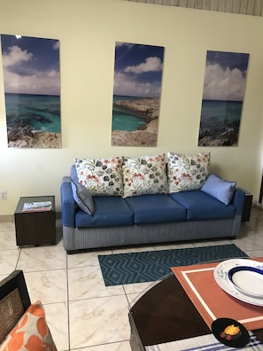 Cozy living space with a blue sofa, coffee table, and framed coastal photographs.