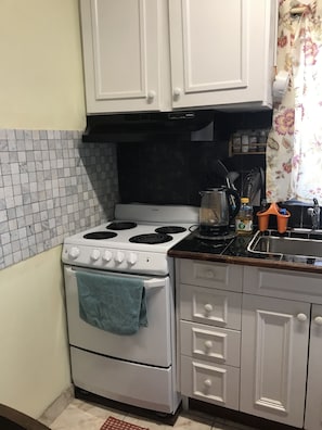 Kitchen features a stove, oven, cabinetry, and a stainless steel sink.