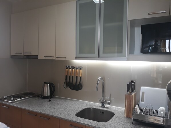 A modern kitchen with a stainless steel sink, a kettle, and a dish rack. - One Pacific Residences (Lapu-Lapu)