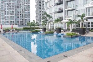A modern hotel pool area with a rectangular pool, lounge chairs, and potted plants. - One Pacific Residences (Lapu-Lapu)