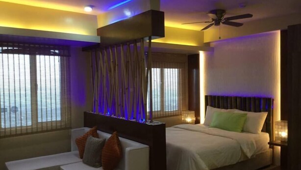 Una habitación de hotel moderna con una cama, una zona de estar y un ventilador de techo.
