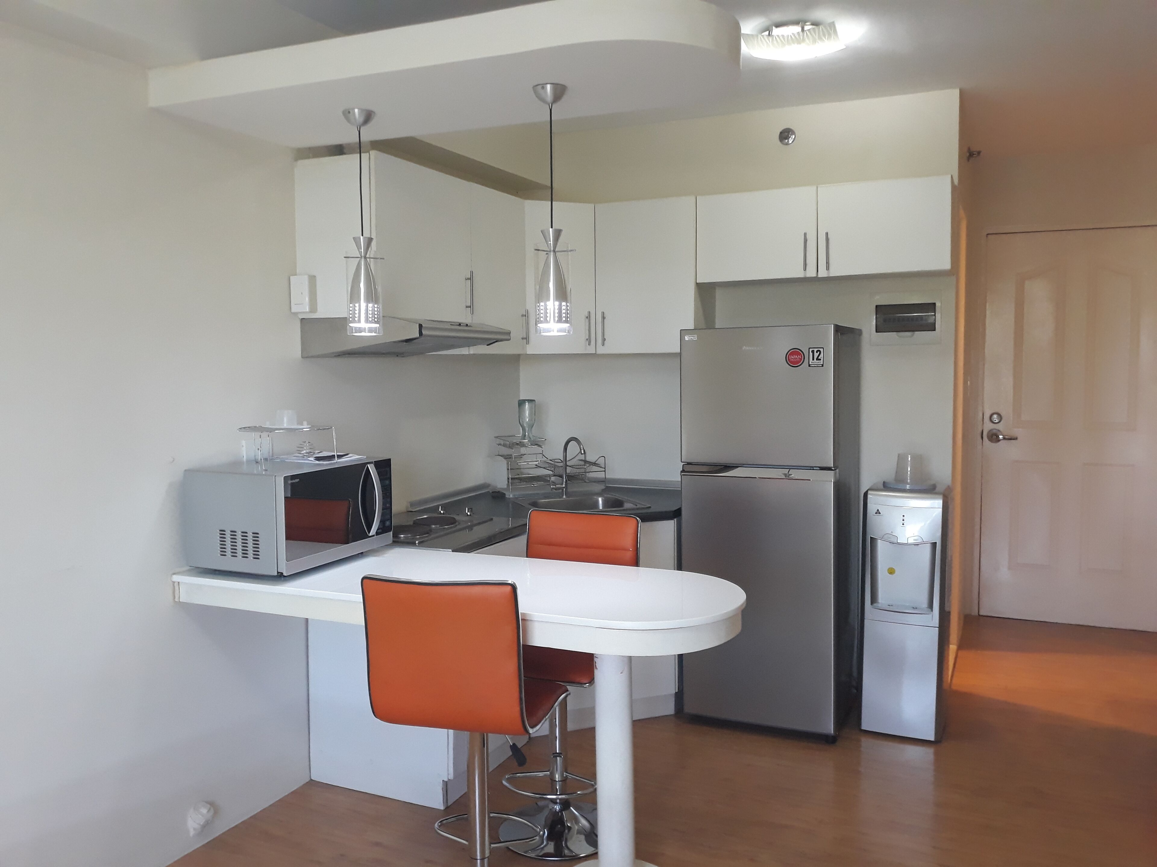 A compact kitchen with a microwave, stove, refrigerator, and a small dining table with two chairs.