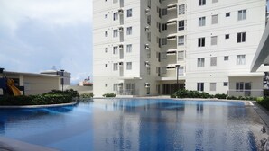 Una piscina rodeada por un moderno edificio de apartamentos con balcones.