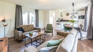 A modern living room with a sofa, coffee table, and a dining area with a table and chairs. - Citta Romana by Interhome (Hellevoetsluis)
