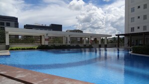 Ein Swimmingpool mit einer weißen Markise, umgeben von Grünflächen und modernen Gebäuden.