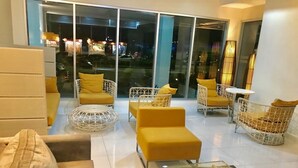 Ein moderner Lounge-Bereich mit gelb-weißen Möbeln, großen Glasfenstern und einem Glastisch.