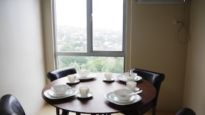 Ein Esstisch mit Schüsseln und Tassen, nahe einem Fenster mit Blick auf eine Stadtlandschaft.