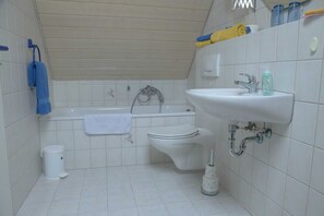 Um banheiro pequeno com banheira, vaso sanitário e pia.