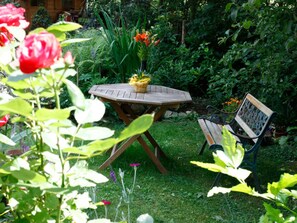 Een tuin met een houten tafel en een bank.