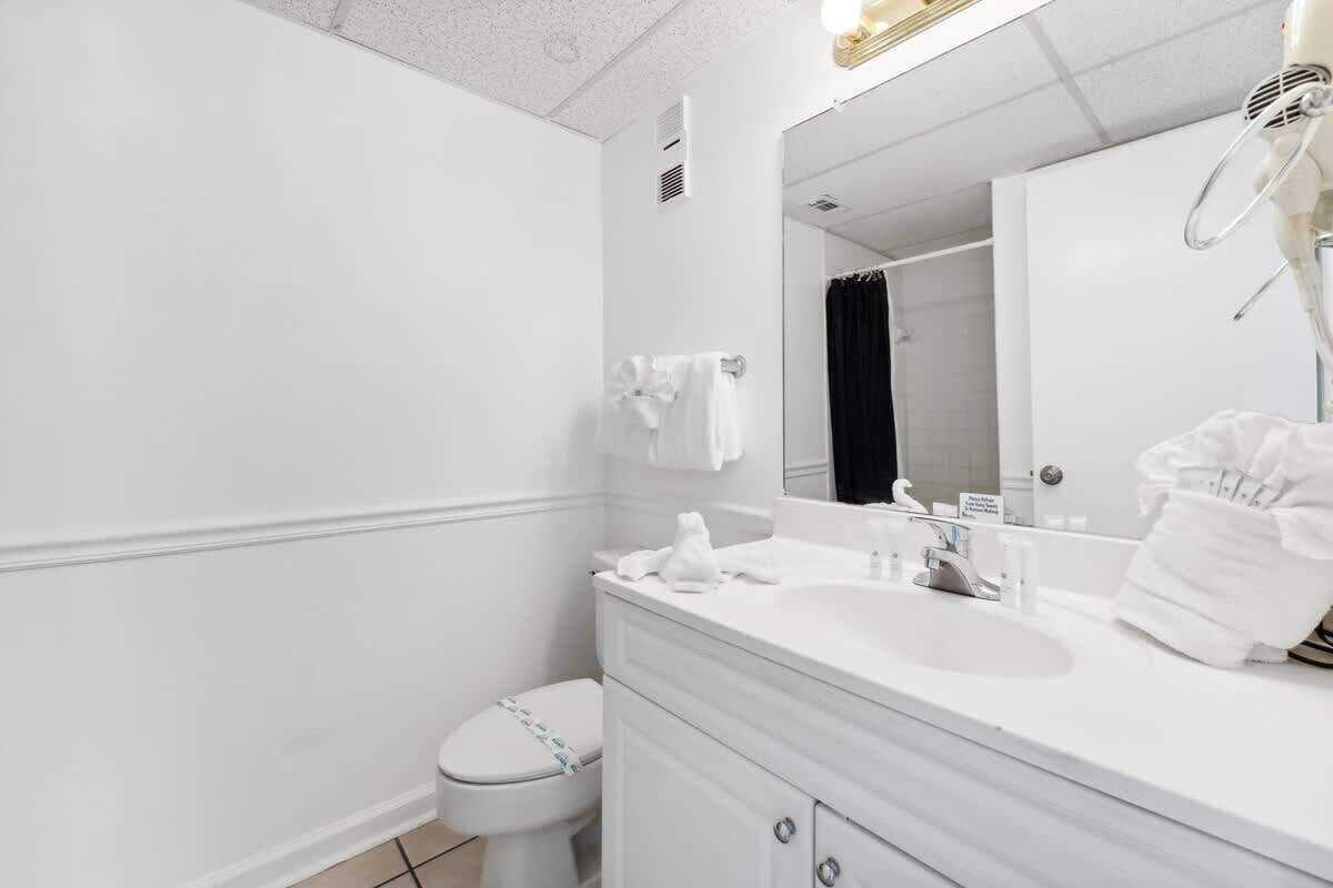 A modern bathroom with a white sink, mirror, and toilet.