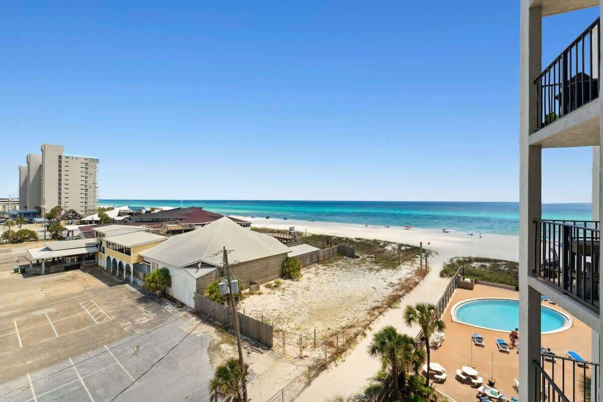 A beachfront property with a swimming pool, a parking lot, and a view of the ocean.